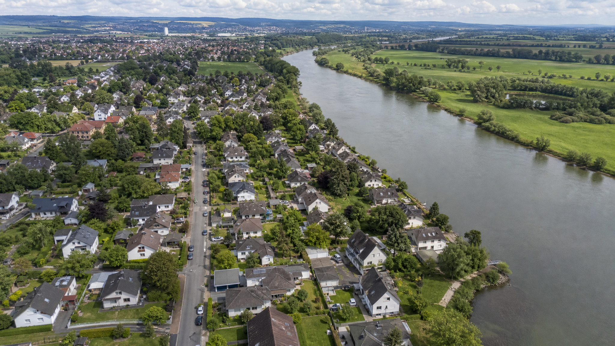 Luftbild eines Wohnviertels am Fluss – die Nähe zum Wasser bestimmt die ZÜRS-Gefährdungsklasse und damit den Beitrag